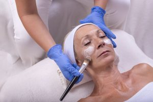 closeup-caucasian-senior-woman-applying-face-cream-beauty-salon_181624-39950