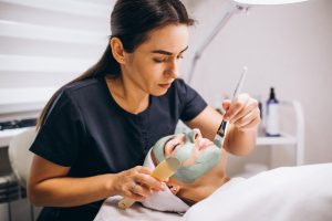 cosmetologist-applying-mask-face-client-beauty-salon_1303-16753